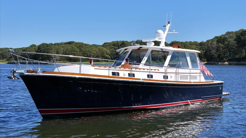 Ballena Yacht Photos Pics 2002 Grand Banks 49 Eastbay HX yacht on calm water, surrounded by lush greenery.