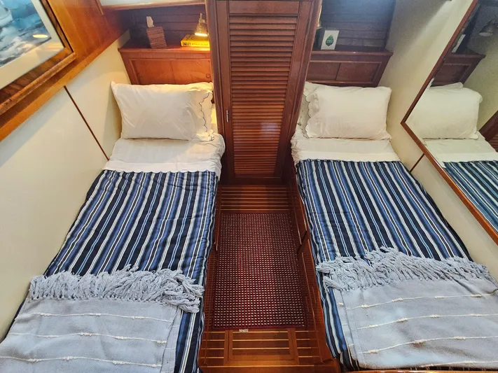 Ballena Yacht Photos Pics Twin beds with striped bedding in a 2002 Grand Banks 49 Eastbay HX cabin.