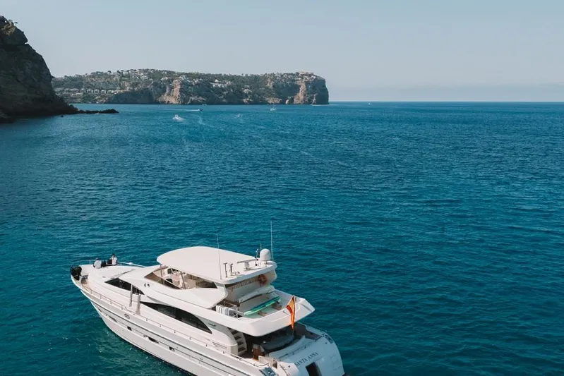  Yacht Photos Pics Luxury Astondoa 82 GLX yacht cruising on clear blue waters, coastal cliffs in the background.