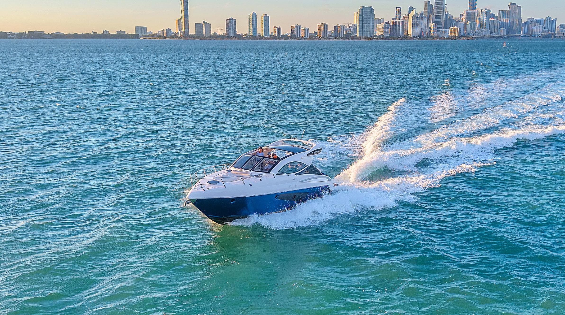 Schaefer 375 yacht cruising on blue ocean with city skyline in background, 2023 model.