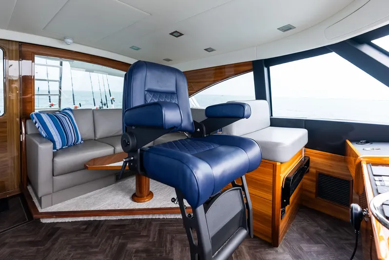Backlash Yacht Photos Pics Luxurious interior of 2023 Viking 72 Enclosed Bridge yacht with plush seating and ocean view.