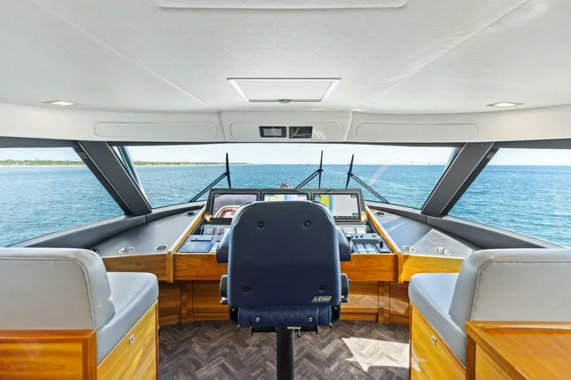 Backlash Yacht Photos Pics Interior view of 2023 Viking 72 Enclosed Bridge yacht helm with ocean backdrop.