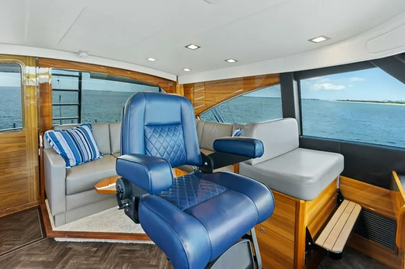 Backlash Yacht Photos Pics Luxurious interior of 2023 Viking 72 Enclosed Bridge yacht with blue seating and ocean view.