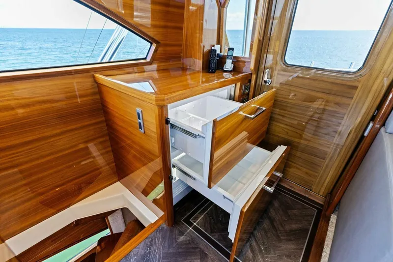 Backlash Yacht Photos Pics Luxurious interior of 2023 Viking 72 Enclosed Bridge yacht with wooden cabinetry and ocean view.
