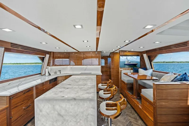 Backlash Yacht Photos Pics Luxurious interior of 2023 Viking 72 Enclosed Bridge yacht with modern kitchen and seating area.