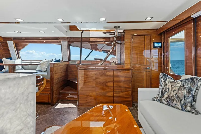 Backlash Yacht Photos Pics Luxurious interior of 2023 Viking 72 Enclosed Bridge yacht with elegant wood finishes and ocean view.