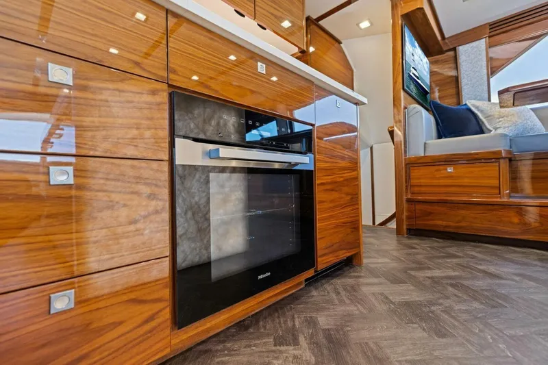 Backlash Yacht Photos Pics Luxurious interior of 2023 Viking 72 Enclosed Bridge yacht with modern kitchen and seating area.