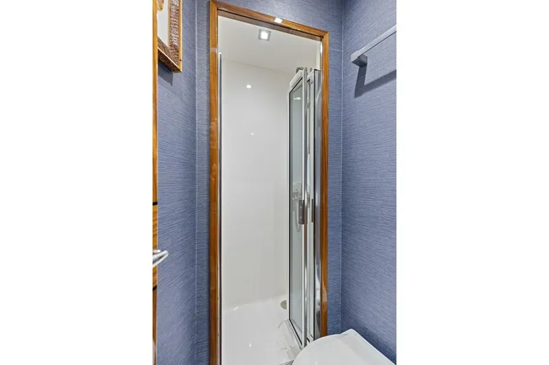 Backlash Yacht Photos Pics 2023 Viking 72 Enclosed Bridge yacht bathroom with glass shower door and blue walls.