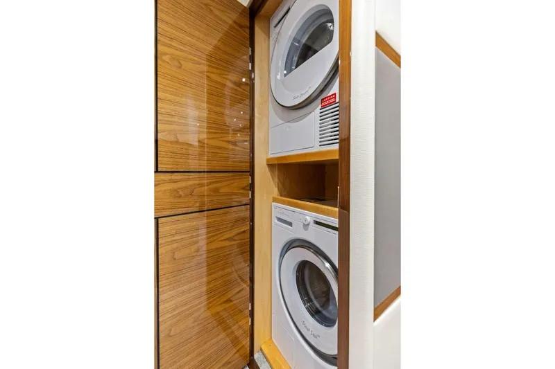 Backlash Yacht Photos Pics Laundry area with stacked washer and dryer in 2023 Viking 72 Enclosed Bridge yacht.