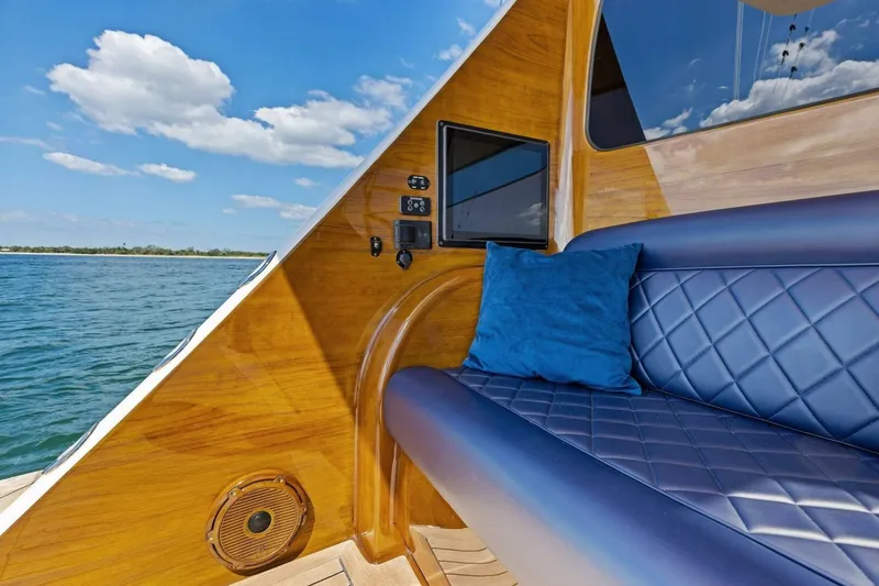 Backlash Yacht Photos Pics Luxurious interior of 2023 Viking 72 Enclosed Bridge yacht with blue seating and wood finish.
