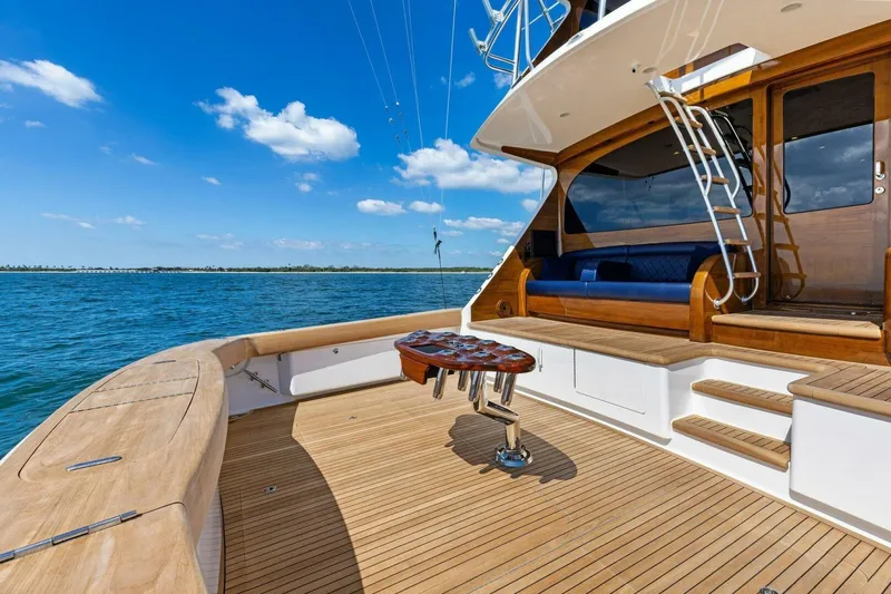 Backlash Yacht Photos Pics 2023 Viking 72 Enclosed Bridge yacht deck with wooden finish, ocean view, and clear blue sky.