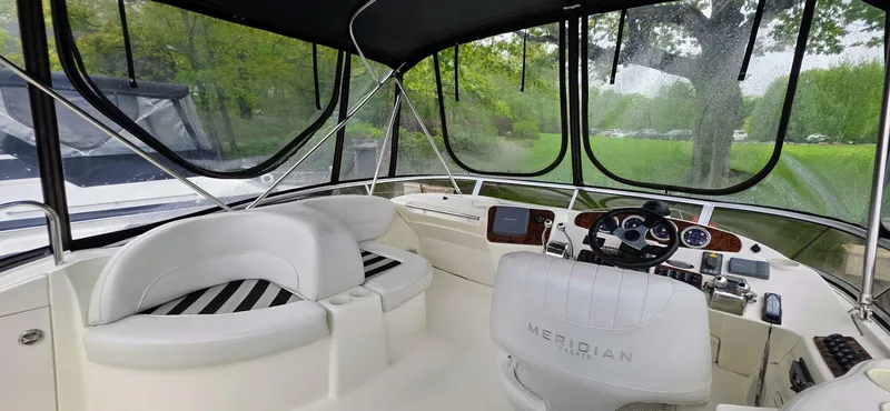  Yacht Photos Pics 2005 Meridian 368 Motor Yacht cockpit with white seating and steering, surrounded by lush greenery.