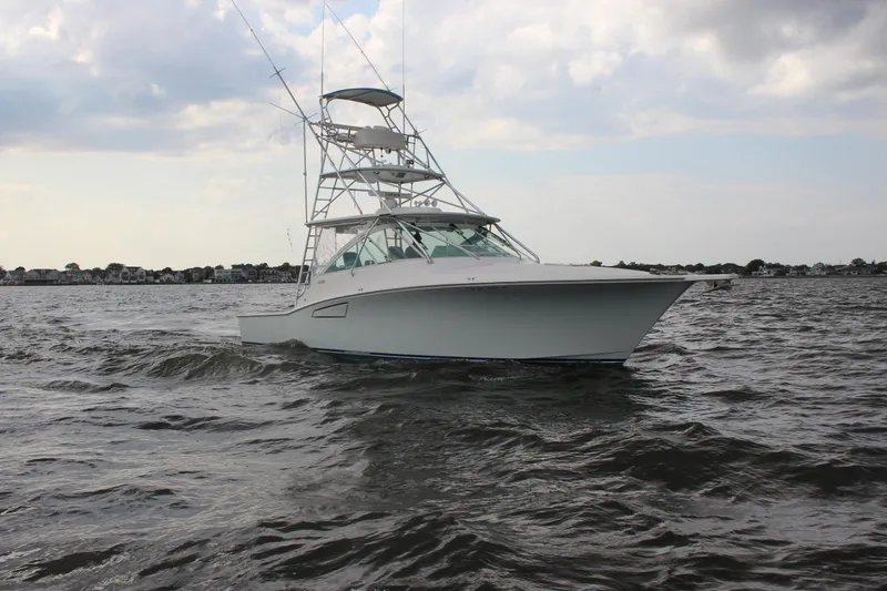  Yacht Photos Pics 2005 Cabo 40 Hardtop Express boat cruising on open water under cloudy sky.