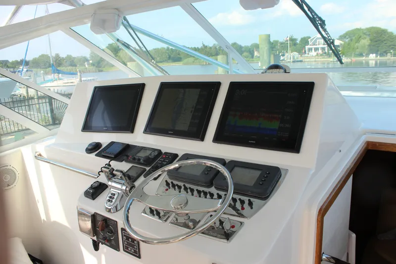  Yacht Photos Pics Control panel of 2005 Cabo 40 Hardtop Express boat with navigation screens and steering wheel.