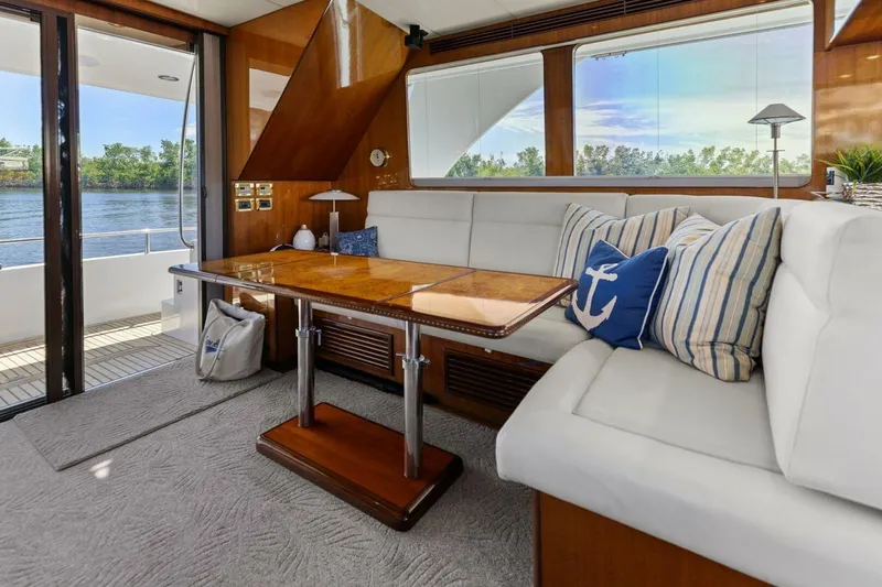 Sunshine And Happiness Yacht Photos Pics Luxurious yacht interior with white seating, wooden table, and nautical-themed pillows.