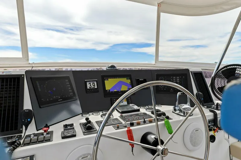 Sunshine And Happiness Yacht Photos Pics Boat cockpit with steering wheel, navigation screens, and controls under a clear sky.
