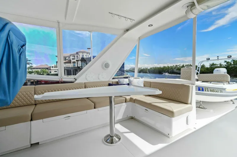 Sunshine And Happiness Yacht Photos Pics Luxurious boat interior with beige seating, table, and scenic waterfront view.