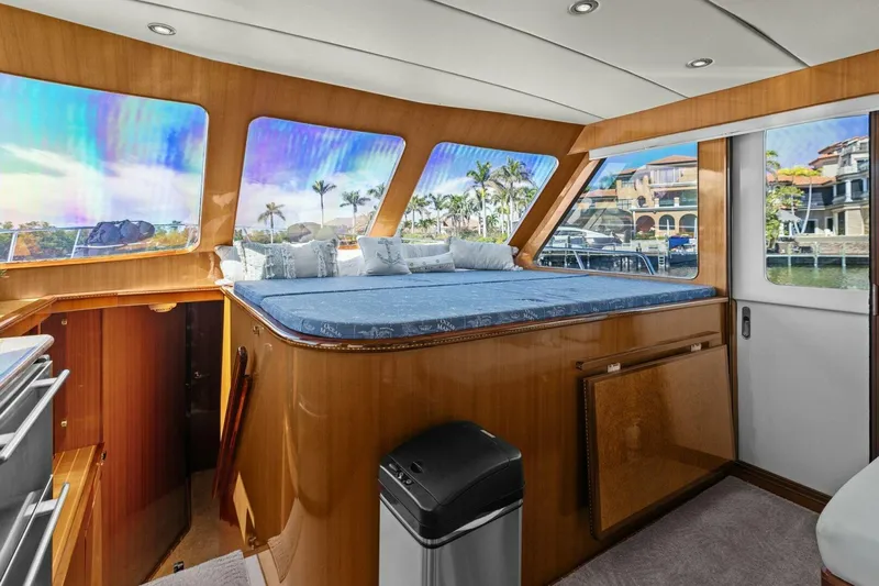 Sunshine And Happiness Yacht Photos Pics Luxurious yacht interior with panoramic windows and plush bedding, overlooking waterfront homes and palm trees.