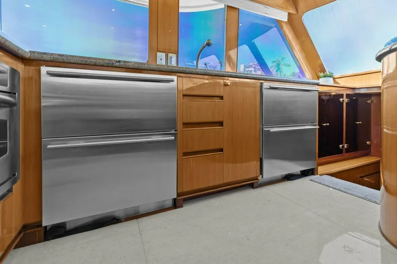Sunshine And Happiness Yacht Photos Pics Modern kitchen with stainless steel appliances and wooden cabinetry, featuring large windows and a scenic view.