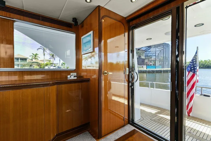 Sunshine And Happiness Yacht Photos Pics Luxurious yacht interior with wooden finish, glass door, and American flag on deck.