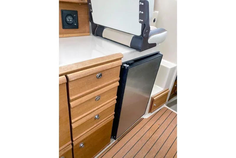  Yacht Photos Pics 2018 Ranger Tugs R-27 interior with wooden cabinetry and compact refrigerator.