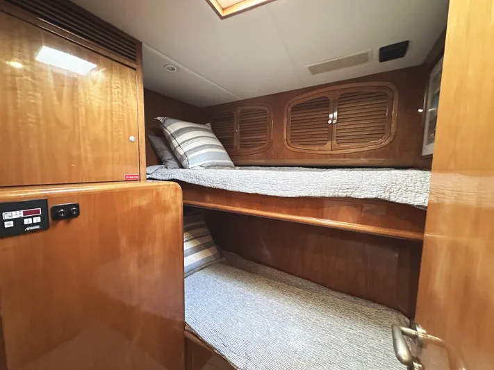 Patrona Yacht Photos Pics Interior of 2000 Mikelson 61 Sportfisher with wooden bunk beds and striped bedding.
