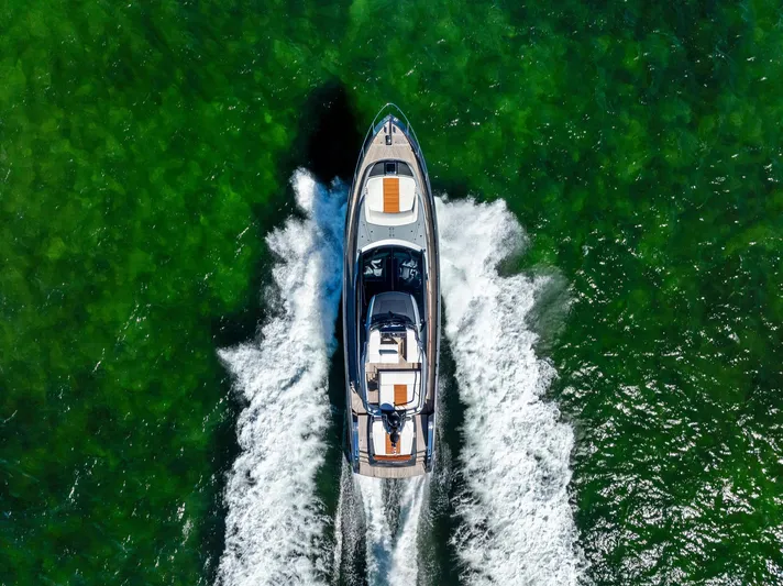 Arcadia Yacht Photos Pics Aerial view of 2020 Riva 66' Ribelle yacht cruising on vibrant green water.