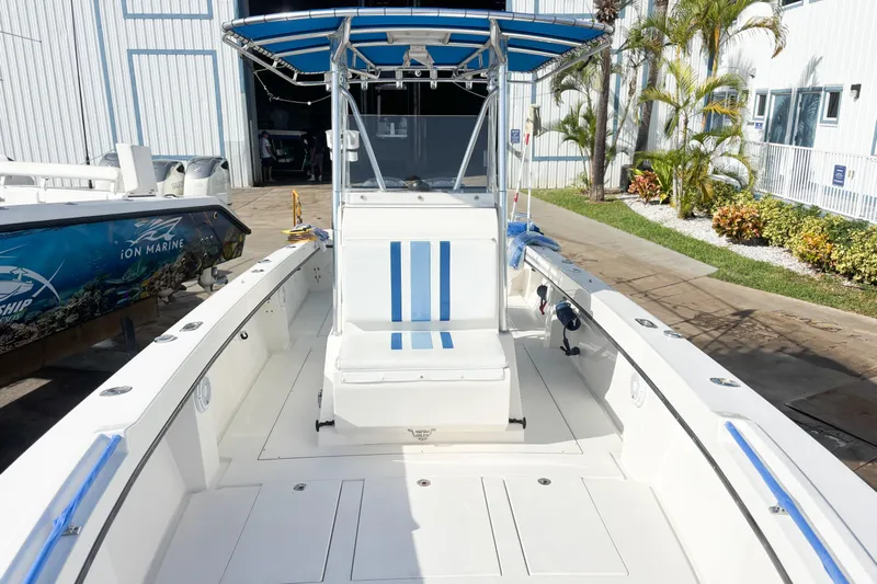  Yacht Photos Pics Whitewater 2016 boat with blue-striped seating and canopy, docked near a building.