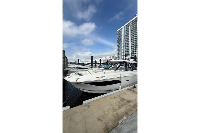 Mercy Yacht Photos Pics 2021 Sea Ray Sundancer 320 docked at marina with modern buildings in background.