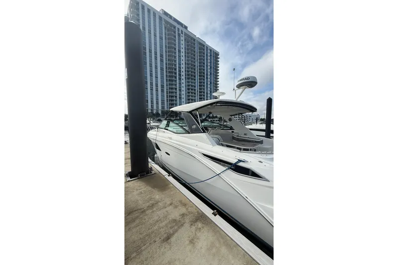 Mercy Yacht Photos Pics 2021 Sea Ray Sundancer 320 docked near modern high-rise building.