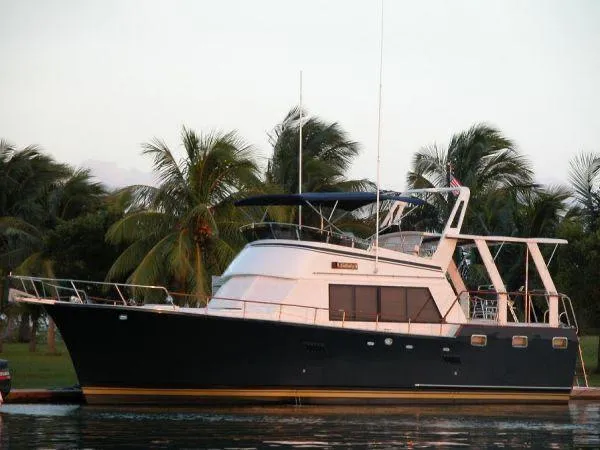  Yacht Photos Pics 1983 Sea Ranger 45 Sundeck yacht docked near palm trees, serene water setting.
