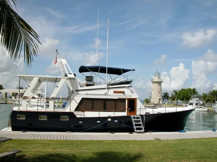  Yacht Photos Pics 1983 Sea Ranger 45 Sundeck yacht docked near a lighthouse under a clear sky.