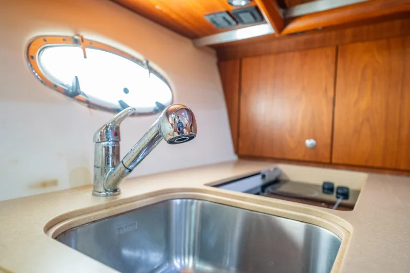 Blue Pearl Yacht Photos Pics 2004 Tiara Yachts 4200 Open kitchen sink with wooden cabinets and porthole window.