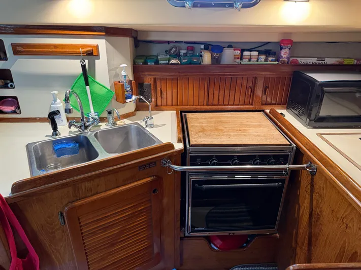 Moonsplash Yacht Photos Pics 1987 Island Packet 38 yacht kitchen with sink, stove, and wooden cabinetry.