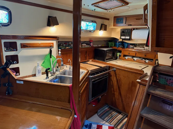 Moonsplash Yacht Photos Pics 1987 Island Packet 38 yacht interior kitchen with wooden cabinetry and modern appliances.