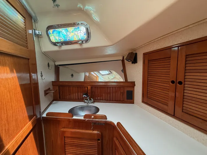 Moonsplash Yacht Photos Pics 1987 Island Packet 38 yacht interior with wooden cabinetry and stained glass window.