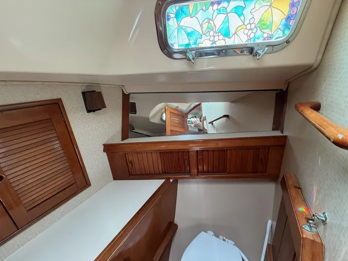 Moonsplash Yacht Photos Pics Interior of 1987 Island Packet 38 sailboat bathroom with stained glass window and wooden cabinetry.