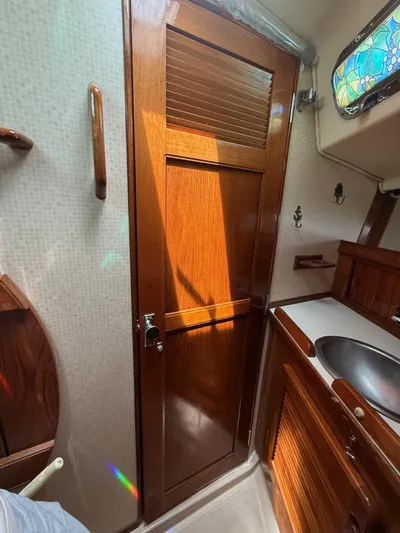 Moonsplash Yacht Photos Pics Interior of 1987 Island Packet 38 sailboat, featuring wooden cabinetry and a stained glass window.