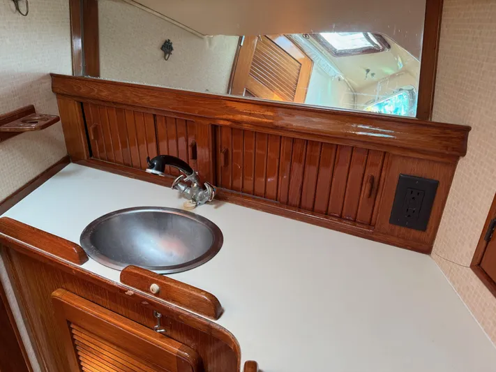 Moonsplash Yacht Photos Pics 1987 Island Packet 38 yacht bathroom with wooden cabinetry, stainless steel sink, and mirror.