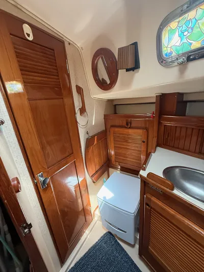Moonsplash Yacht Photos Pics 1987 Island Packet 38 yacht interior with wooden cabinetry, sink, and stained glass window.