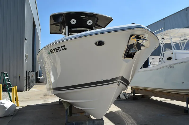  Yacht Photos Pics 2022 Pursuit S 268 Sport boat in storage, front view, near industrial building.