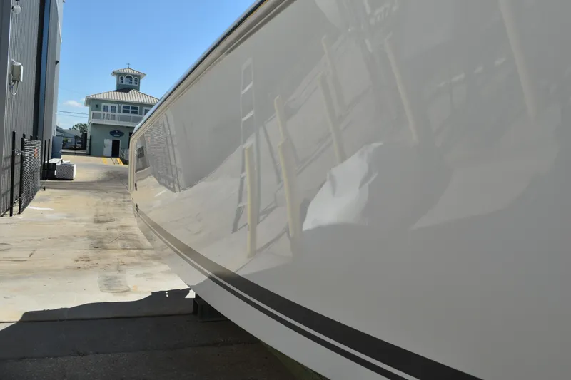  Yacht Photos Pics 2022 Pursuit S 268 Sport boat side view with reflection, docked near a building.