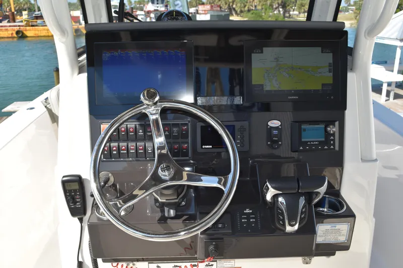  Yacht Photos Pics 2022 Pursuit S 268 Sport boat dashboard with steering wheel, navigation screens, and controls.