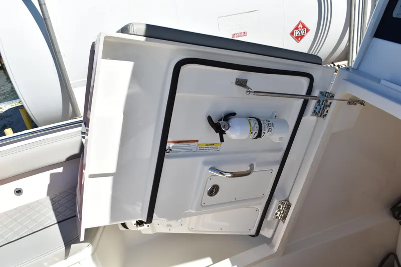  Yacht Photos Pics 2022 Pursuit S 268 Sport boat interior with open storage compartment and fire extinguisher.