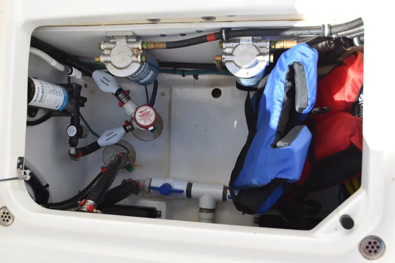  Yacht Photos Pics 2022 Pursuit S 268 Sport boat storage compartment with life jackets and plumbing components.