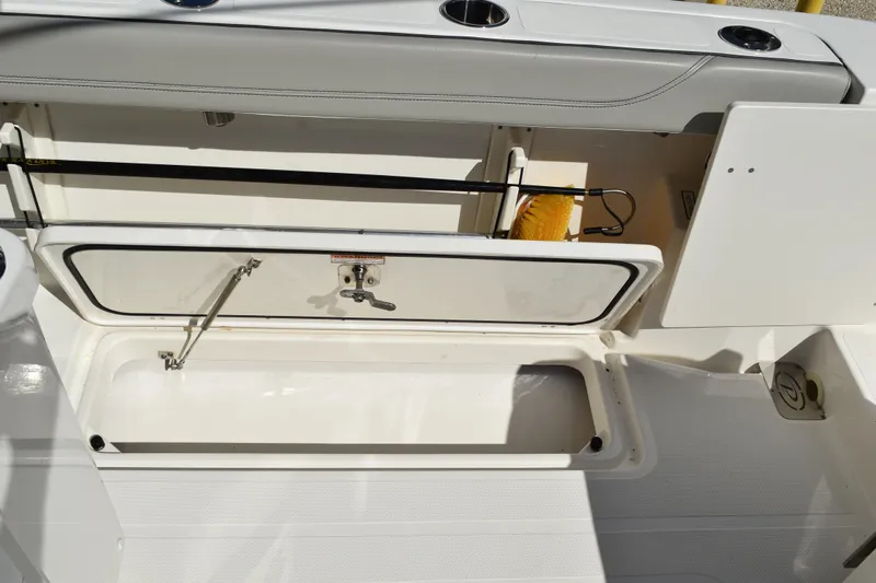  Yacht Photos Pics 2022 Pursuit S 268 Sport boat storage compartment with open hatch and cleaning brush.