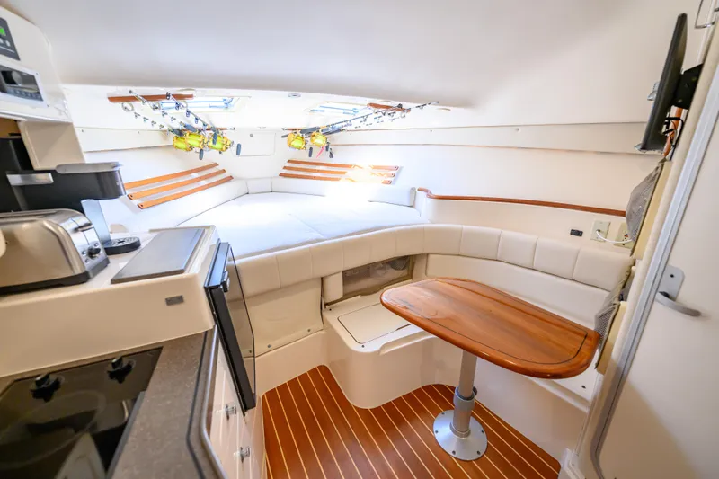 Sur Reel Yacht Photos Pics 2003 Grady-White Express 330 cabin interior with kitchenette, seating, and fishing rods.