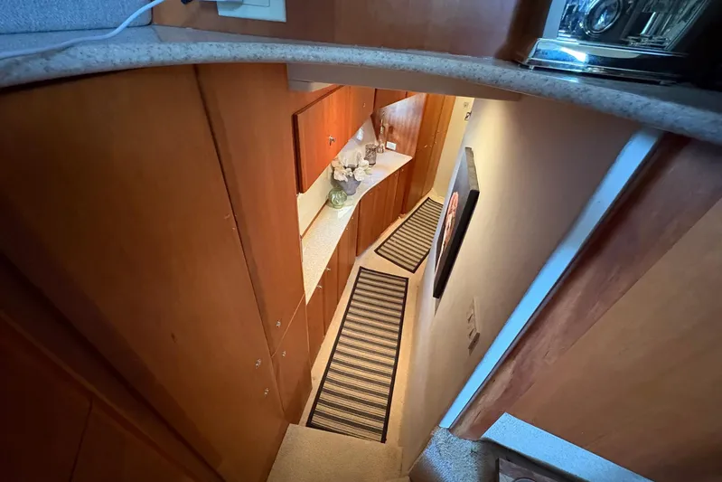 Lola's Ark III Yacht Photos Pics Interior view of 2001 Silverton 453 Motor Yacht hallway with wooden cabinets and striped rugs.
