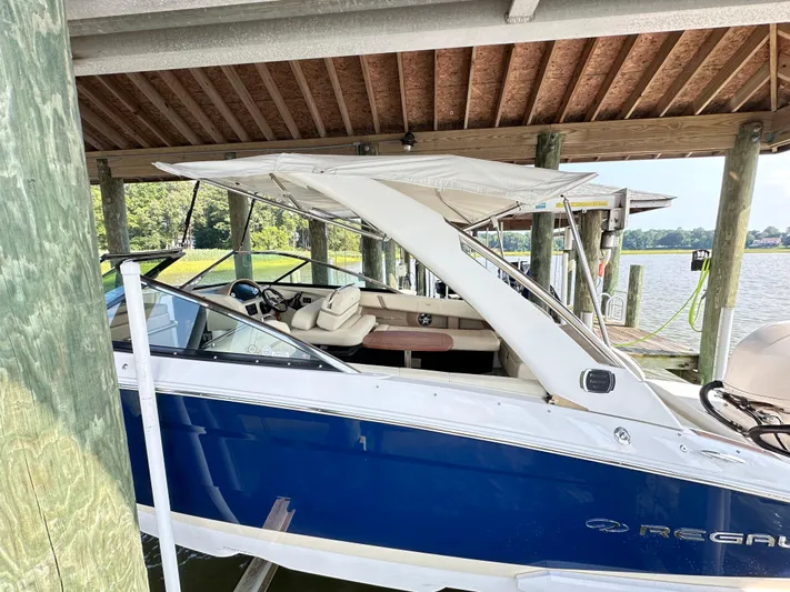  Yacht Photos Pics 2019 Regal 29 OBX boat docked under a wooden shelter by the water.