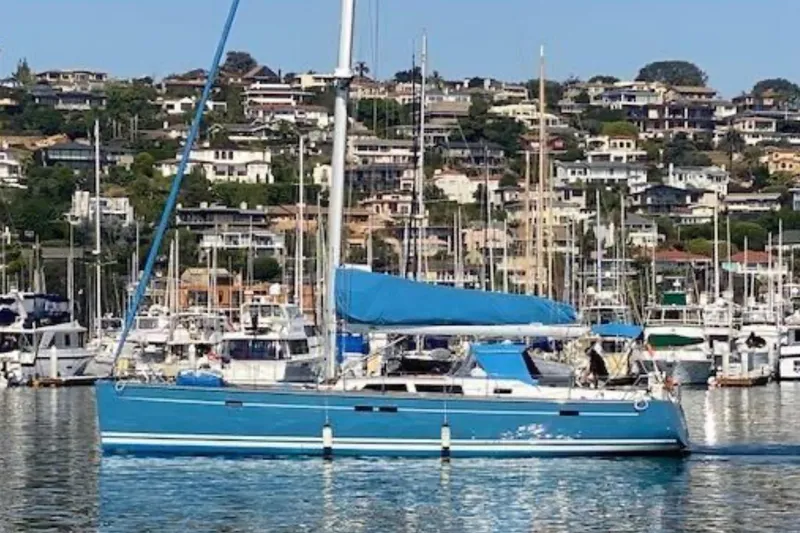 Blue Pearl Yacht Photos Pics Blue 2008 Hanse 540e sailboat docked in a marina with hillside houses in the background.